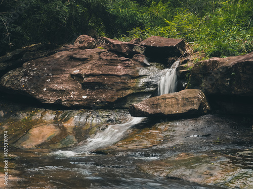 Powerful waterfall stream flowing rapidly during the rainy season, capturing the raw energy and movement of nature. 