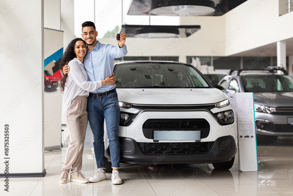 © Prostock-studio - Cheerful young arab man and woman posing over their new auto in showroom, showing key from luxury automobile and hugging, copy space. Middle-eastern family buying new comfortable car © Prostock-studio - Cheerful young arab man and woman posing over their new auto in showroom, showing key from luxury automobile and hugging, copy space. Middle-eastern family buying new comfortable car