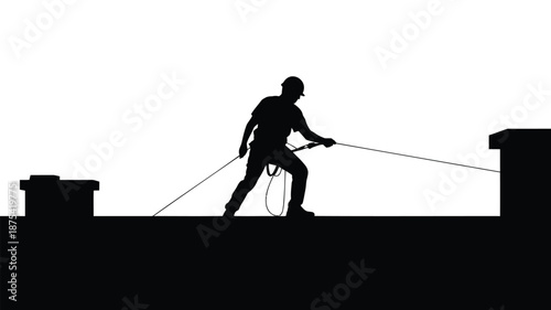 Silhouette of man climbing with rope between two buildings