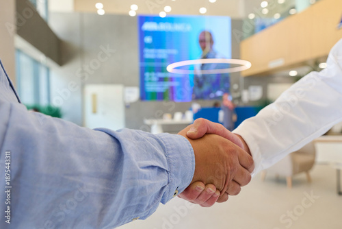 Business professionals engage in a handshake inside a modern office lobby during a meeting in the afternoon