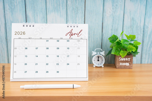 April Monthly desk calendar for 2026 year and alarm clock.