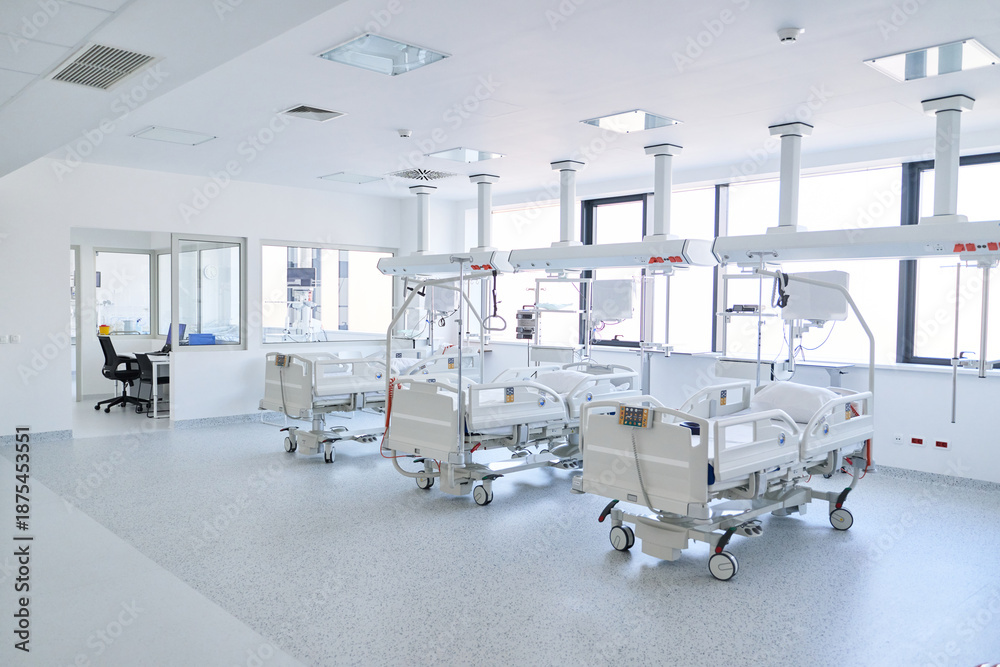 Fototapeta premium Modern hospital room with multiple empty beds and bright windows in a healthcare setting