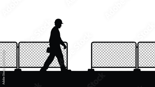 Construction worker walking past metal barriers on site