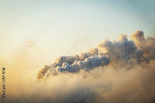 Smoke moving up polluting atmosphere during sunrise. Smoke from industrial chimneys, environmental problems, air pollution.