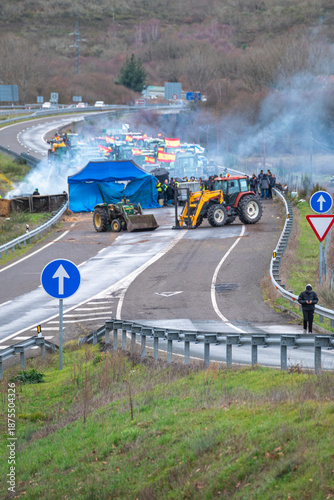 Fotografia Tractors and smoke blocking a road in Spain the concept of an agricultural strik