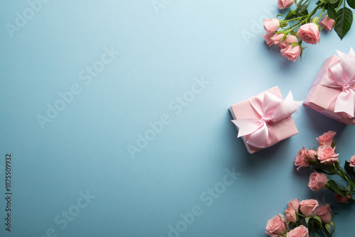 Pink gift, present box decorated with ribbon bow, pink rose flowers on blue background top view. Valentine's day, 14 February, birthday, 8 march women's day gift. Love and romance. Spring.