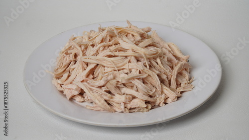 steamed chicken that has been shredded on a clear plate and isolated on a white background
