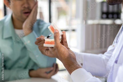 Fotografi Man with toothache consults with doctor in examination room