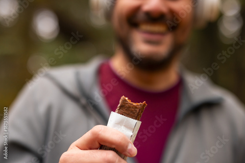 Fotografía Smiling man holding a protein bar after workout
