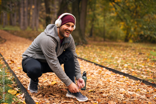 Man tying shoelace before autumn workout in park