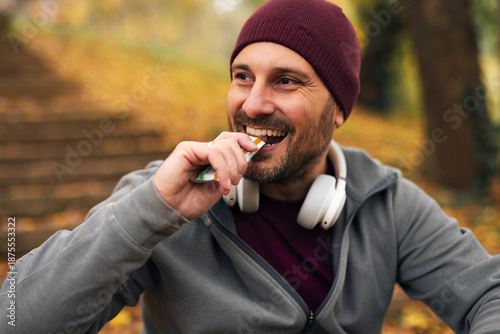 Bilde på lerret Happy man eating energy bar during autumn workout break