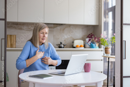 Foto Senior woman suffering from chest pain at home while communicating with a doctor