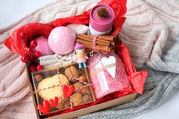 gift box idea for Valentine's day, 14 february. cosmetic care set, bath salt, sweets, cinnamon sticks, decor, knitted scarf close up. personalized gift basket for family, friends, girl. top view