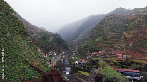 Misty valley with steep green terraces and winding road