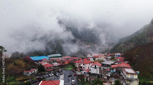 Shrouded village on mountain slopes with winding pathways and dense housing
