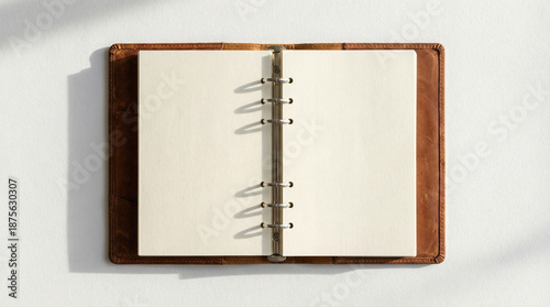 Agenda vintage de piel con anillas hecha a mano con papel blanco reciclado para tomar notas del día a día como agenda, diario, cuaderno de viajes, con iluminación natural sobre un fondo blanco.