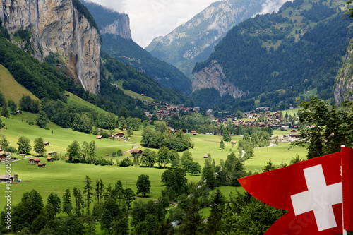 Wallpaper Mural Summer scenery of beautiful Lauterbrunnen village with the famous Staubbach waterfall tumbling down the rocky cliff and chalet houses in the green grassy valley, in Bernese Oberland, Switzerland Torontodigital.ca