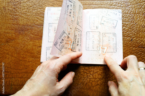 Billede på lærred Female hand flipping stamped passport pages with many border stamps