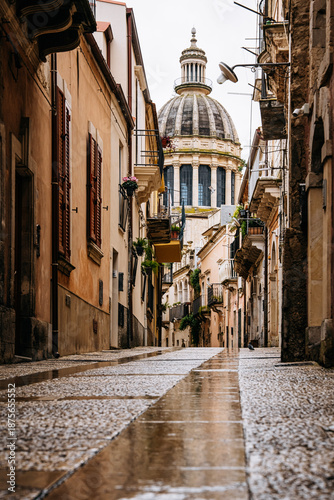 Back Side Of Duomo Di San Giorgio In UNESCO City Ragusa, Sicily: Narrow Historic Street Leading Toward Baroque Cathedral Dome And Stone Facades