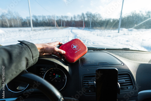 Driver Checking Red First Aid Kit On Dashboard At Snowy Roadside, Hands Inspecting Clasp And Compact Interior, Smartphone Mounted, Daylight Clarity, Proactive Safety Routine