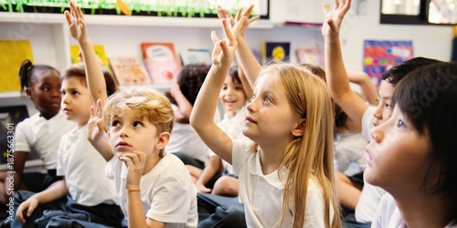 Bilde på lerret Diverse group of young students, boys and girls, sit on the floor in a classroom raising hands
