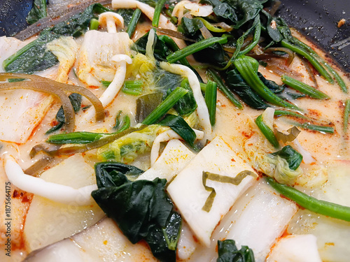 Spicy mala soup served in a black bowl, filled with vegetables and herbs, rich chili broth, hot flavor, Asian comfort food style.