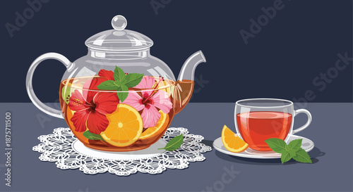 Beautiful glass teapot filled with hibiscus flowers and orange slices next to a cup of warm red tea on a grey background.