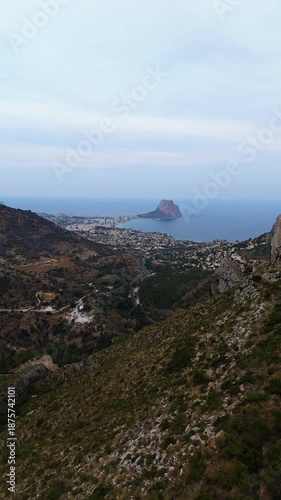 Scenic coastal view transitions from hillside to ocean, showcasing vibrant landscape, camera pans smoothly to reveal expansive horizon and distant rock formation