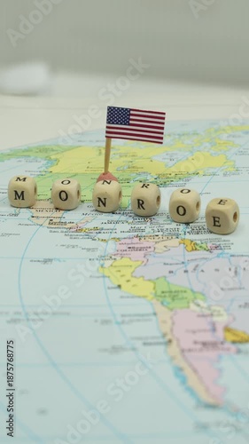 United States foreign policy concept of the Monroe Doctrine represented on a map of the American continents with wooden cubes and a flag, symbolizing opposition to European colonialism