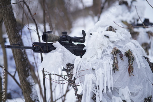 Foto A special forces scout peers through the forest using optics, his white camouflage breaking up his silhouette