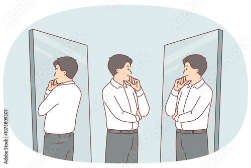 Business man looks in mirror trying on new formal clothes and touches chin with smile