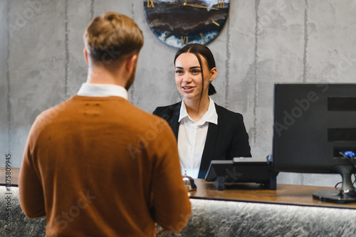 Photos Guest discussing check in with hotel receptionist at front desk