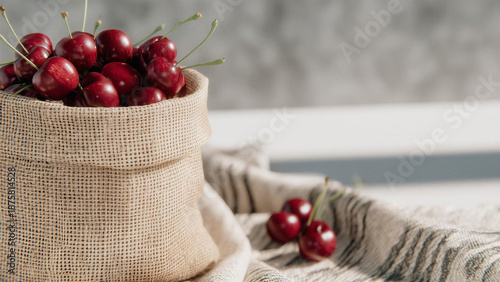 Fresh red cherries in burlap on a rustic linen background – a still life of natural fruits with soft lighting, organic style, and the mood of a summer harvest.