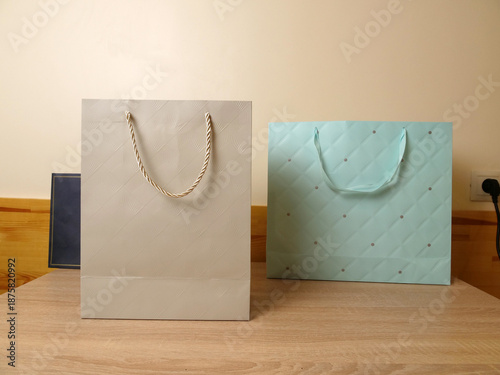 Canvastavla Two paper gift bags with handles standing on a wooden surface against a plain wall