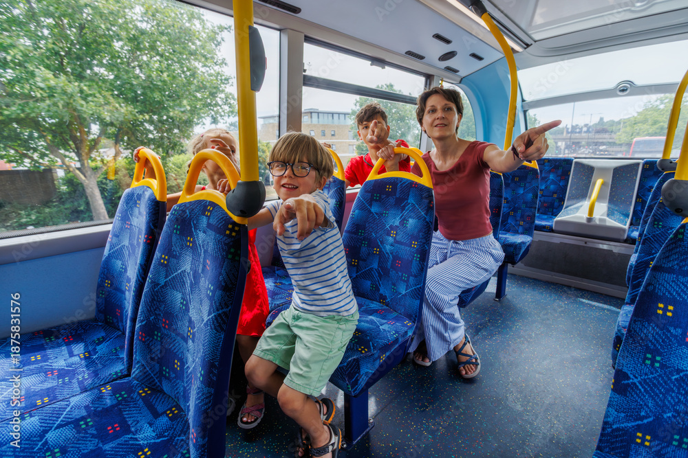 Fototapeta premium Family of four enjoying a fun bus ride while pointing outside