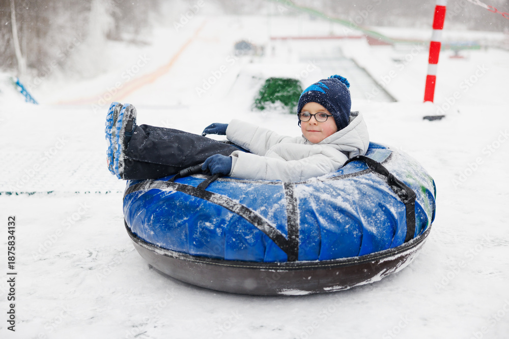 Fototapeta premium Child Enjoying Snow Tubing Adventure on a Winter Day