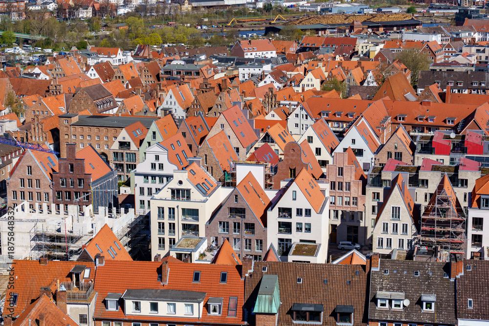 Fototapeta premium A city Lubeck in Germany with many red and white houses. The houses are all different sizes and shapes. The houses are all lined up in a row