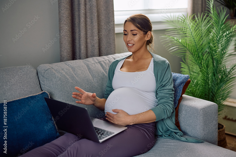 Obraz premium Happy expectant mother talking during video call over a laptop at home.