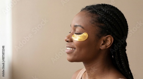 African woman applying gold eye patches for skincare