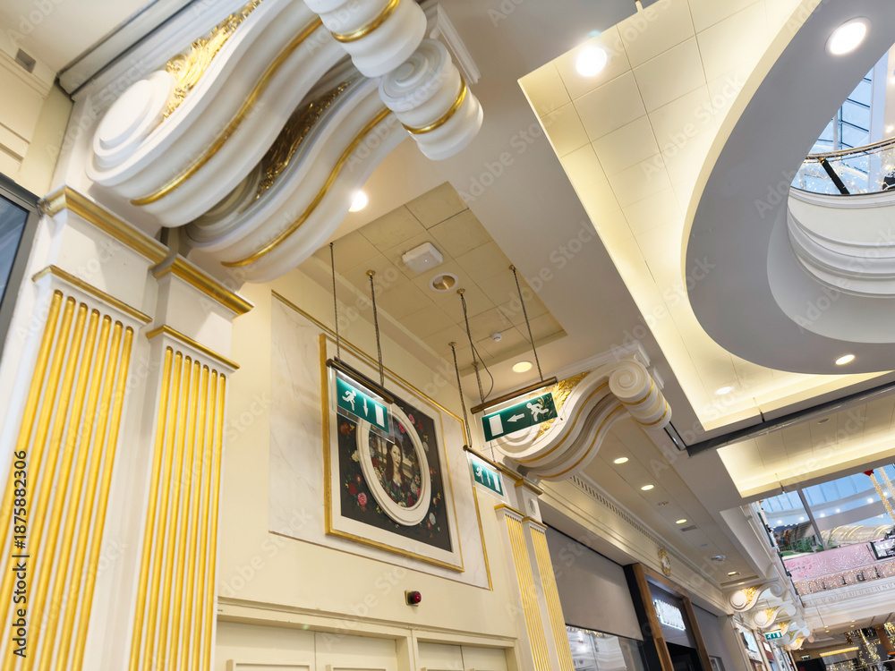 Fototapeta premium Elegant indoor Trafford Centre atrium with gold decorative columns and curved ceiling lighting in Manchester UK mall