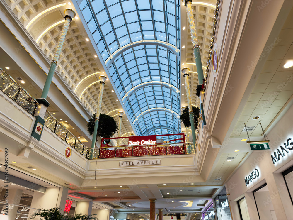 Naklejka premium Indoor Trafford Centre shopping mall atrium with glass skylight, festive decorations, and Be's Cookies cafe in Manchester