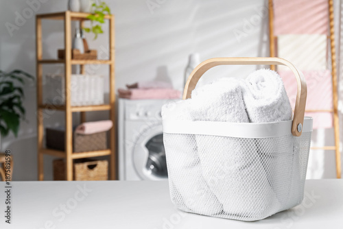 Laundry basket with towels on white table indoors. Space for text