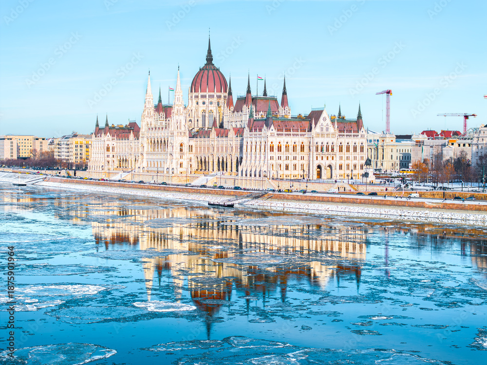 Obraz premium The Parliament of Hungary in Icy Winter time and it's mirrored picture on the freezing Danube, Budapest Hungary