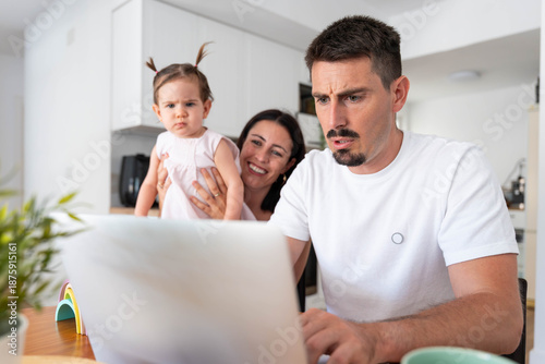Bild auf Leinwand Father working anxiously from home with a laptop, multitask parenting while moth