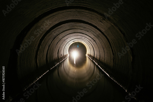 Foto Inside dark round underground urban flooded sewer tunnel with water reflection