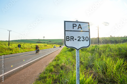 Billede på lærred BR-230 road sign on the Transamazonian Highway with cars and motorcycle in backg