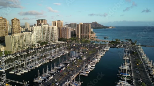 Drone aerial view of Waikiki marina and harbor with sailboats, city skyline and Diamond Head coastline in Honolulu Hawaii USA
