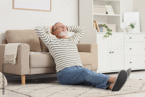 Happy senior man resting near sofa at home