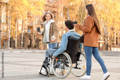 Wallpaper Mural Young man in wheelchair and his friends with coffee cups on city square Torontodigital.ca