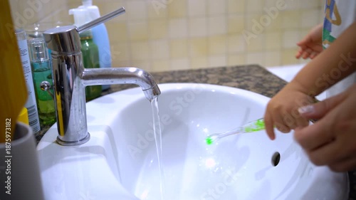 the child washes his pens under the faucet and picks up a toothbrush